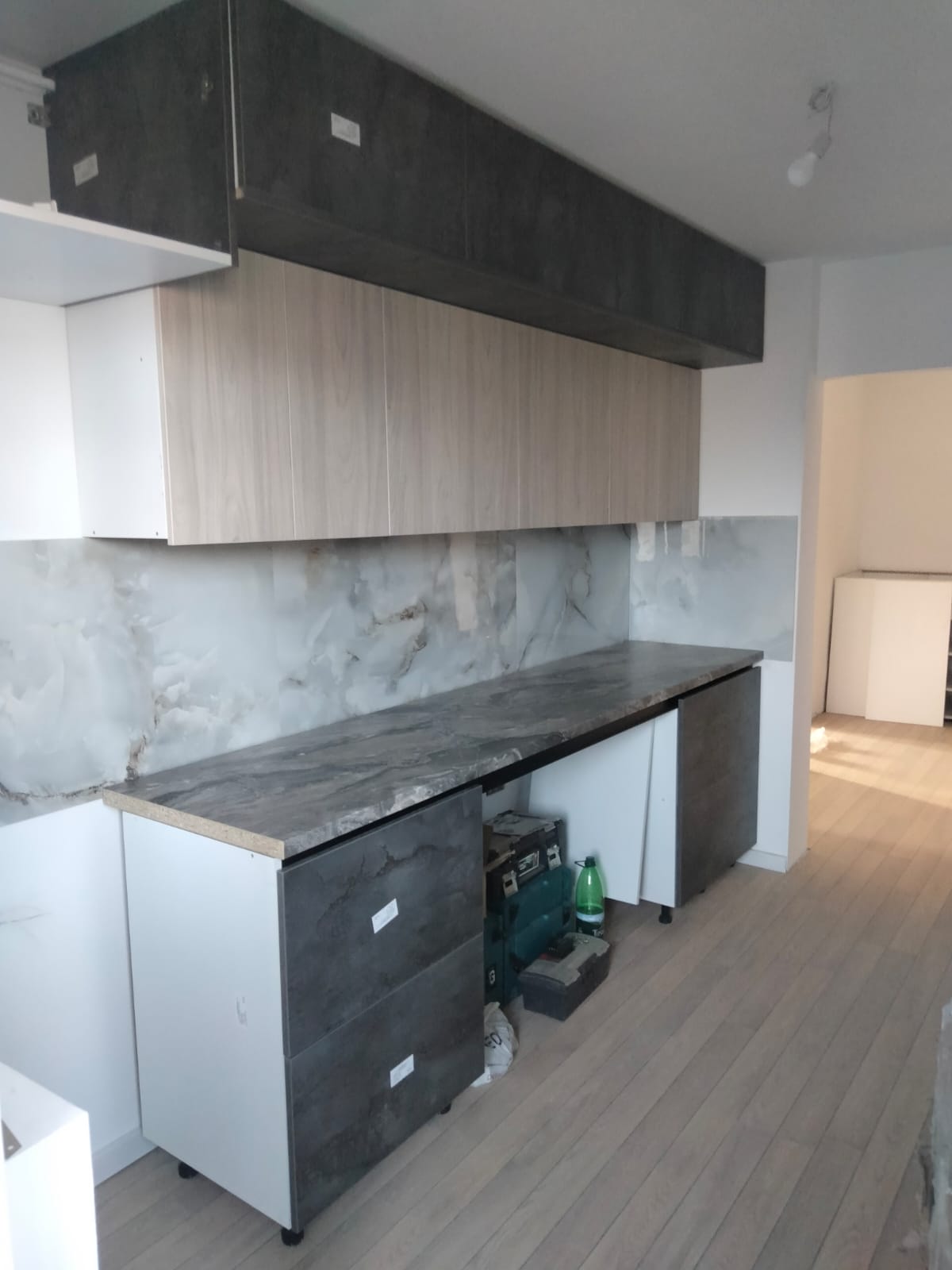 Bucătărie modernă cu mobilier gri și blat cu aspect de piatră